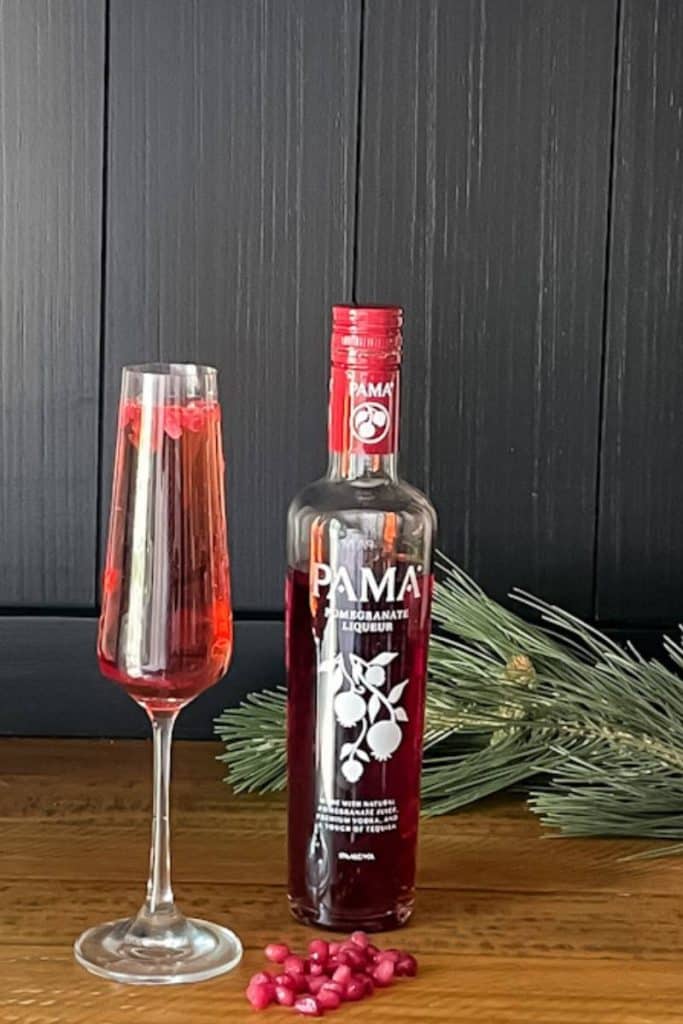 bottle of Papa pomegranate liqueur next to a pomegranate champagne cocktail glass