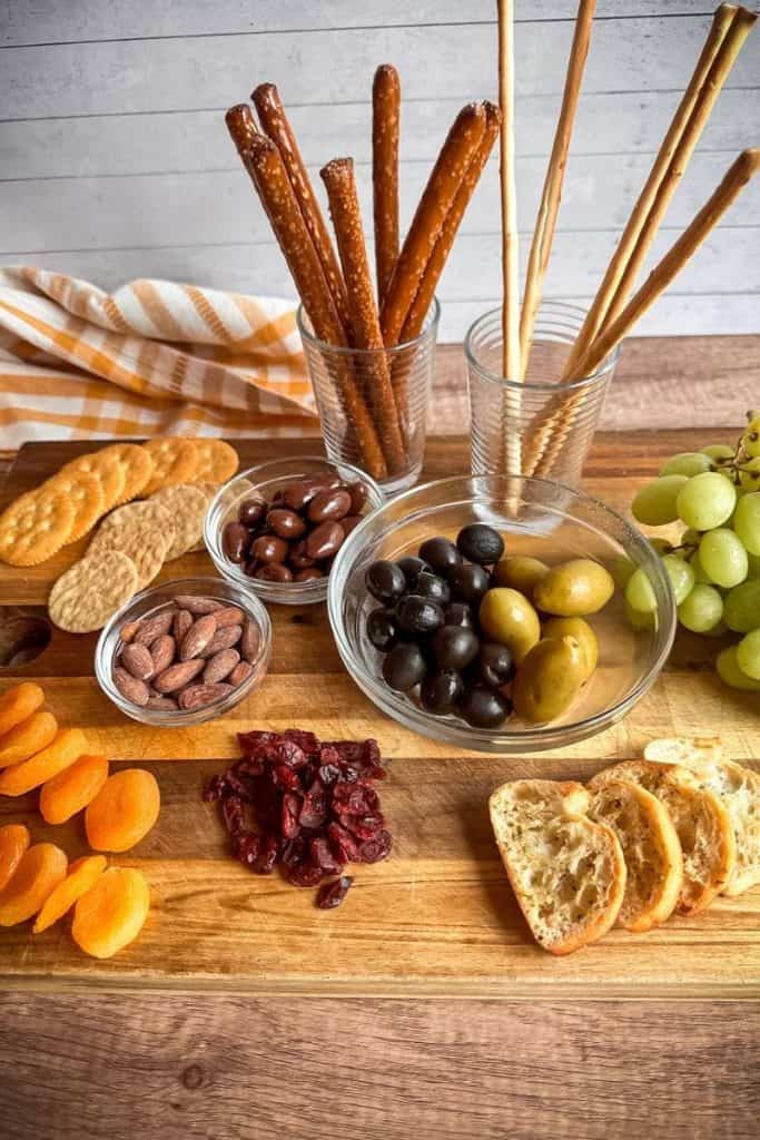 items for charcuterie board; olives, nuts, grapes, crackers, breadsticks