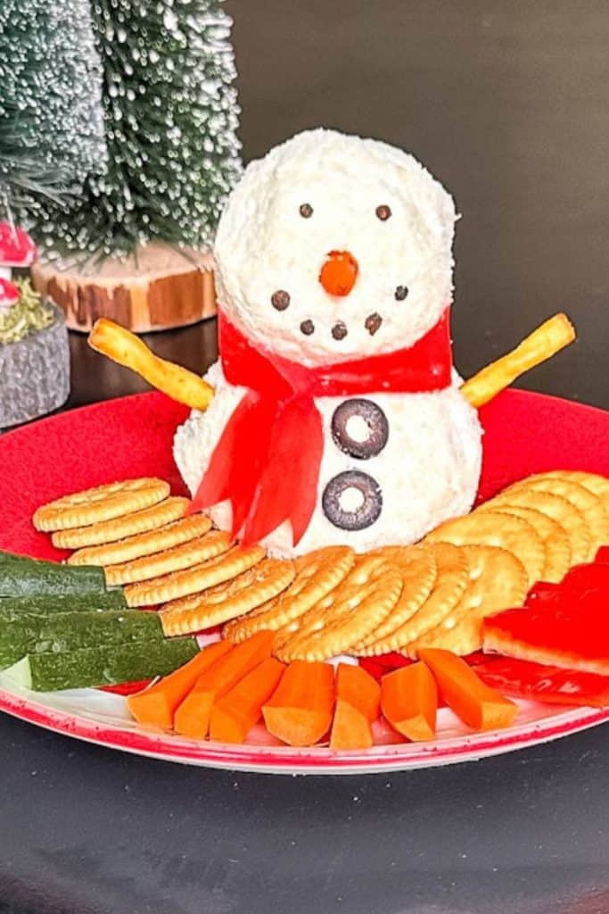 snowman cheeseball on plate with crackers and veggies