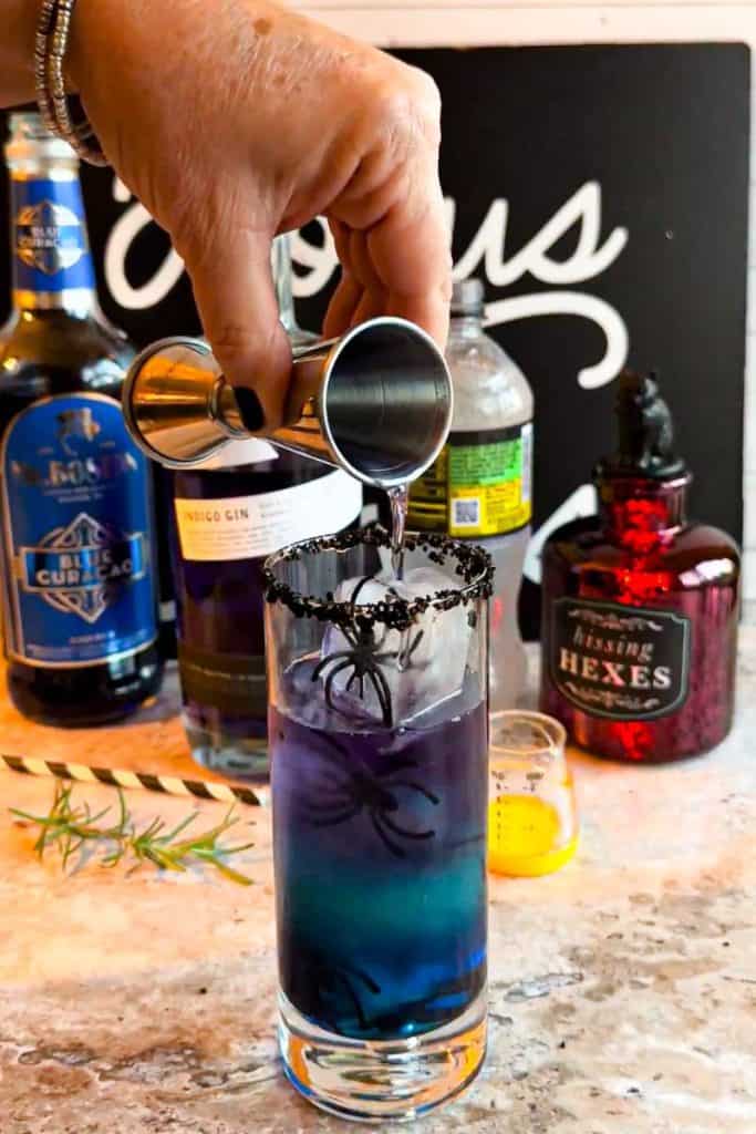 pouring empress gin into glass of Hocus Pocus Witches Brew