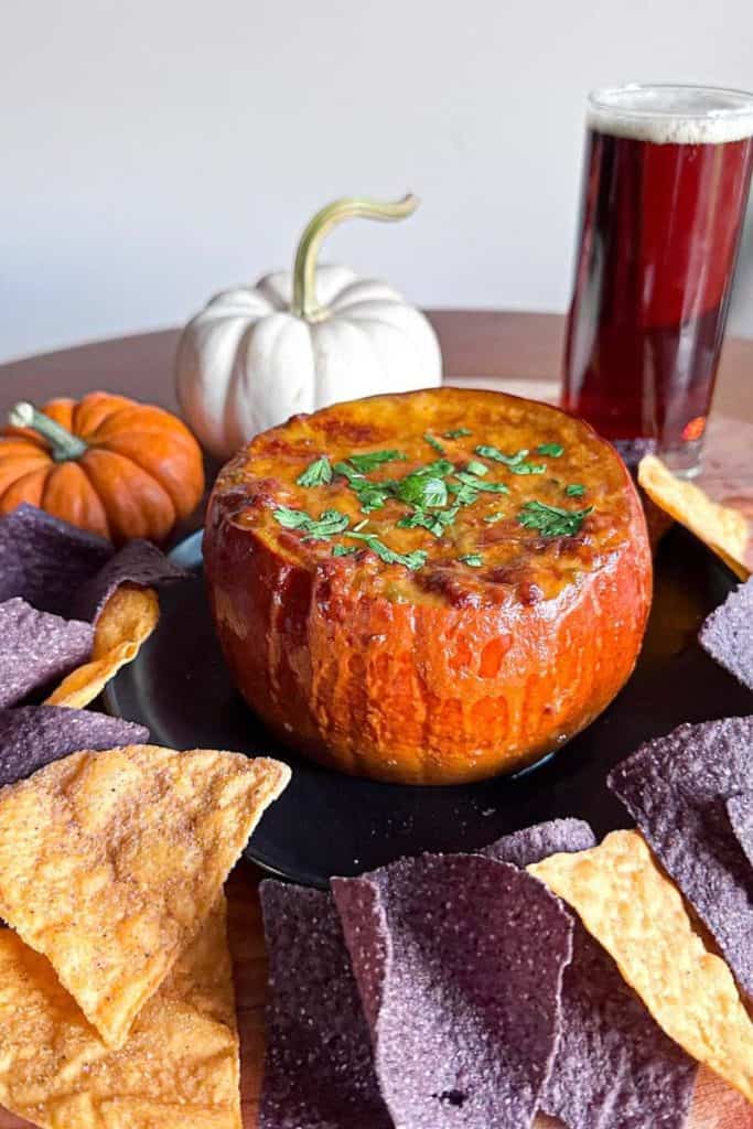 queso dip in pumpkin surrounded by tortilla chips