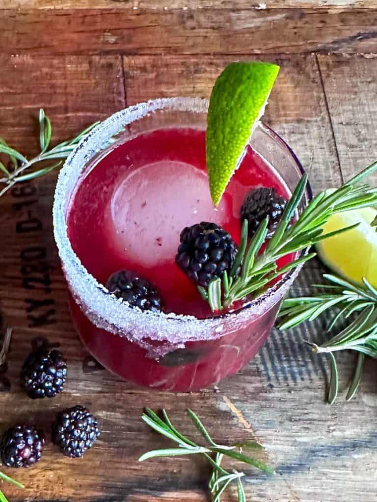 blackberry margarita garnished with lime and blackberries and rosemary
